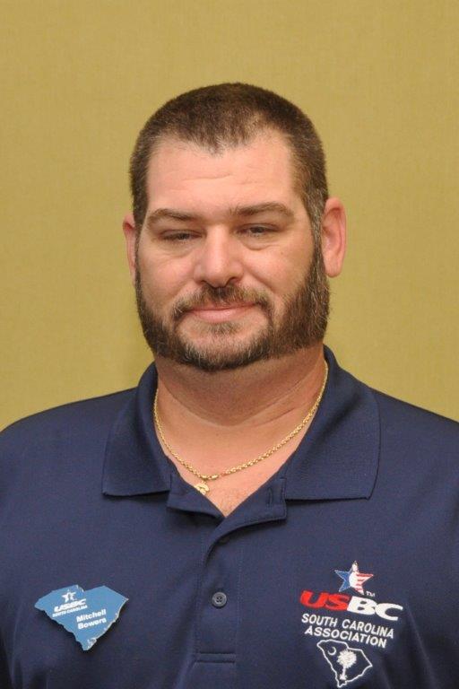 A man with a beard and mustache wearing white shirt.